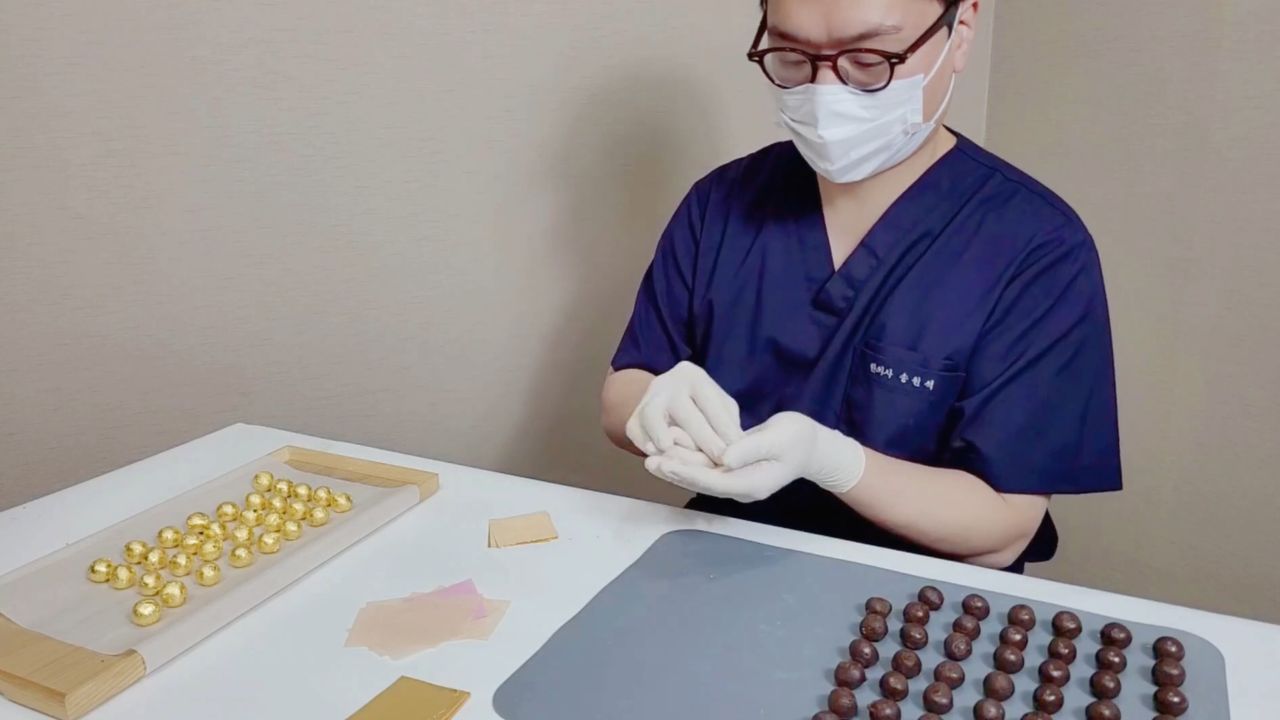원장이 금박을 입힌 공진단을 하나씩 정리하는 모습